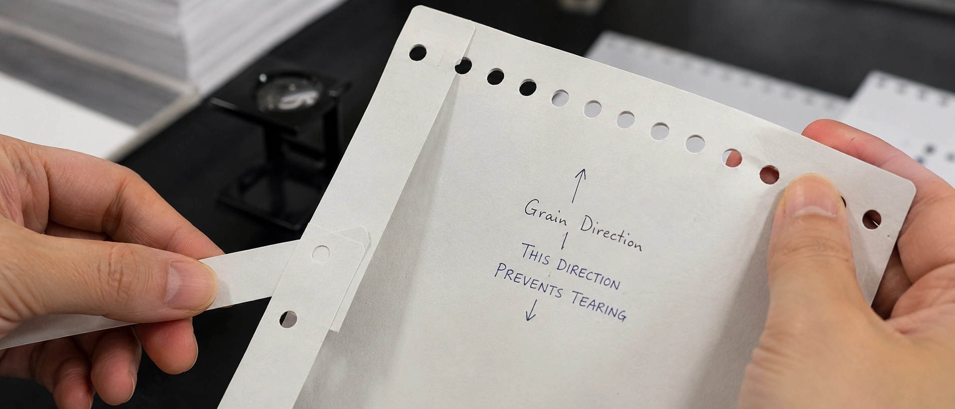 Close-up of paper grain direction testing for spiral binding to prevent hole tearing and book warping Close-up of paper grain direction testing for spiral binding to prevent hole tearing and book warping